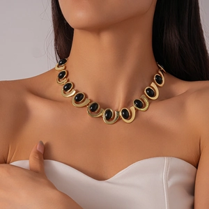 Detail of vintage gold U-link chain necklace with oval black resin stones on model