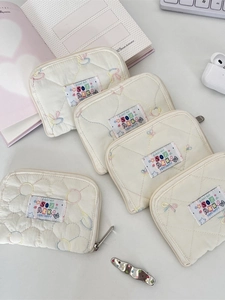 Off-white quilted mini wallet with floral embroidery and branding on a desk set