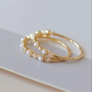 Elegant gold ring with small pearls and zircons in a minimalist light luxury style