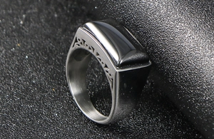 Macro detail of men's stainless steel signet ring with black stone and cut-out pattern