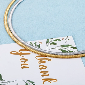 Detailed view of polished gold and silver flat snake chain necklaces on a gift card