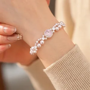 Elegant double-row pearl bracelet with pink zircon centerpiece on a female wrist