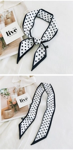 Polka dot skinny silk scarf shown knotted and laid flat with aesthetic lifestyle props