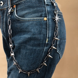 Close-up of punk style trousers chain with metal spikes and star pendant on blue jeans