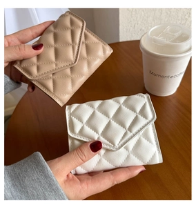 Close-up of elegant quilted beige and white clutches on a wooden coffee table