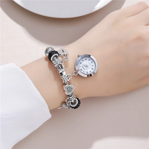 Silver beaded charm bracelet watch with heart and crown pendants on a female wrist
