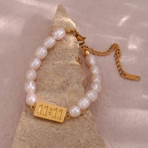 Detailed macro of irregular freshwater pearls and golden 11:11 plate on jewelry