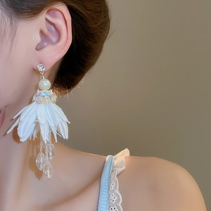 Close-up of white chiffon flower tassel earrings with crystals and pearls on model