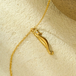 Macro shot of gold seahorse pendant necklace with zircon eye detail on stone
