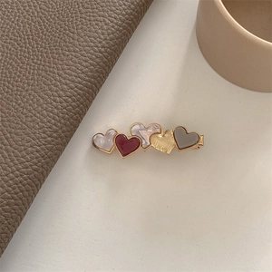 Detail of burgundy heart-shaped acetate hair clip with golden metal spring fastener
