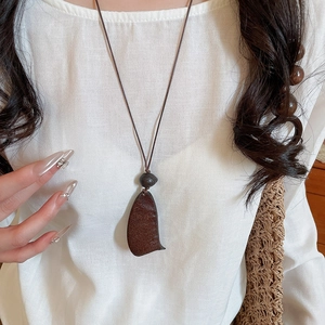 Ethnic teardrop pendant necklace in deep brown wood on white linen garment background