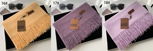 Detailed view of three soft tassel scarves in ginger and purple with leather brand tags