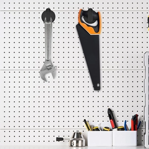 Black magnetic hooks on pegboard holding a silver wrench and hand saw in a workshop