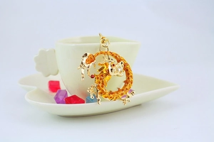 Detail of a textured golden dragon earring hanging on a white heart-shaped saucer