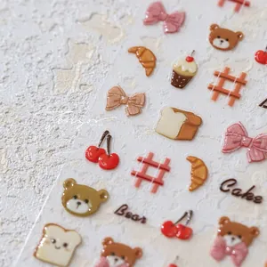 Macro shot of 3D embossed bear and cake themed nail art stickers with glossy details