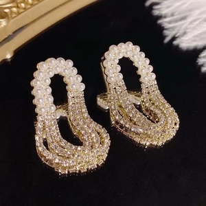 Macro shot of silver pearl tassel earrings with zircon crystals on a reflective surface