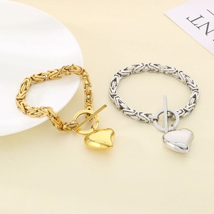 Gold and silver heart pendant bracelets with OT clasp on minimalist beige fabric background