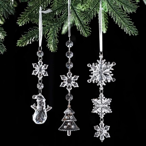 Three-piece clear acrylic Christmas snowflake ornaments with ribbons on pine branches