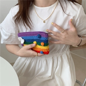 Detail of a rainbow crochet mini bag with colorful pom-poms and white cloud charm