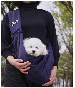 Outdoor model wearing dark blue soft cotton pet sling bag carrying a small white dog