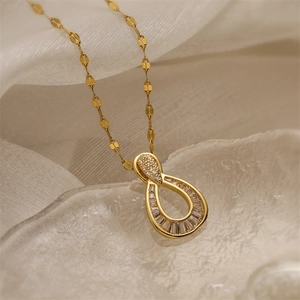 Macro view of gold teardrop pendant necklace with zircon inlay on white silk fabric