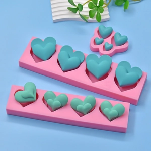 Stampi a cuore in silicone rosa per sapone e candele su sfondo blu con decoro bianco