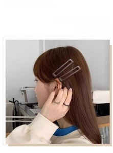 Détail de barrettes rectangulaires mates marron foncé portées sur les cheveux
