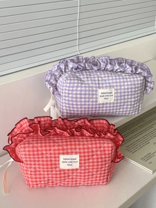 Detail of berry colored quilted makeup bags with ruffled edges and ribbon zip pulls