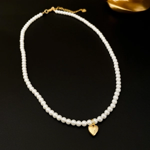 Elegant white faux pearl necklace with a 3D gold heart pendant on a black background