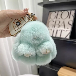 Detail of mint green plush rabbit keychain with soft fur texture and gold hardware