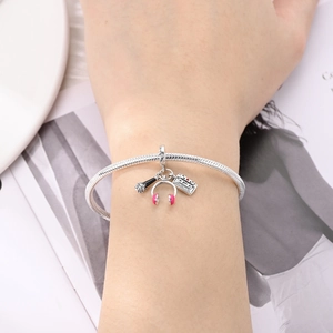 Close-up of music-themed silver snake chain bracelet with headphone and tape charms