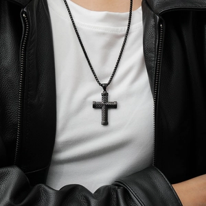 Close-up of black cross necklace with herringbone texture on a male model in leather jacket