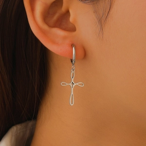 Detailed close-up of a silver hoop earring featuring a layered hollow cross pendant