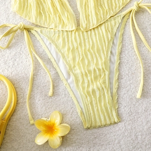 Flat lay of pale yellow halter bikini featuring vertical ribbed texture and side ties