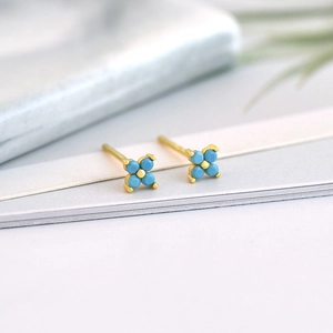 Macro view of gold flower earrings with turquoise blue petals and polished metal base