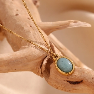 Macro view of vintage 18K gold plated necklace with oval grey aventurine on a wooden branch