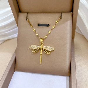 Close-up of a gold dragonfly pendant necklace with inset crystals on a jewelry box