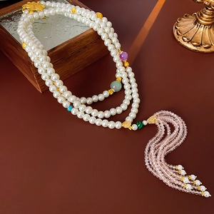 Detail of beaded pearl necklace with colorful glass beads and a pink silk tassel