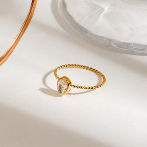 Detailed close-up of a golden rope band ring featuring a teardrop shaped clear zircon