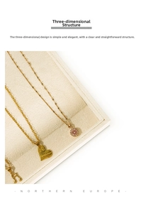 Detailed view of gold necklaces with heart and gem charms on a beige velvet jewelry tray