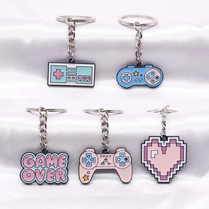 Five retro gaming enamel keychains including gamepads and pixel heart on white silk cloth