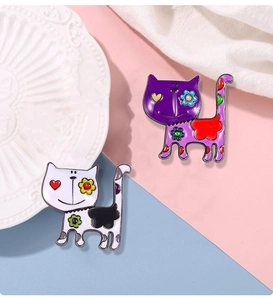 Detail of colorful cat enamel pins with floral patterns on pink and blue background