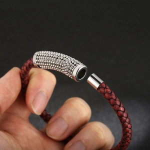 Handheld view of woven leather bracelet with stainless steel magnetic clasp and beads