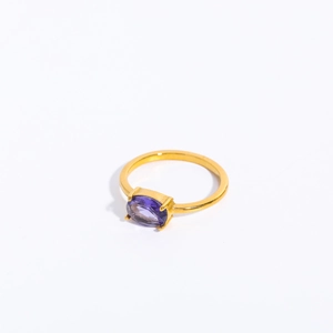Macro detail of a gold ring featuring a polished purple oval zircon stone