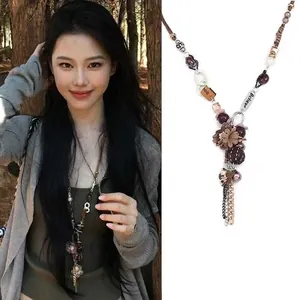 Detail of wax rope necklace with fabric flower charm and Believe engraved metal tag