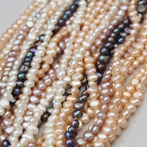 Macro shot of assorted baroque freshwater pearl strands in white, purple, and gold tones