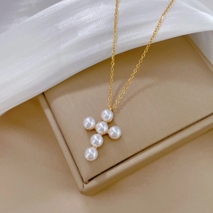 Macro detail of gold-plated cross pendant featuring six lustrous white pearls on a chain