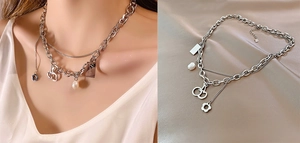 Detail of double-layered titanium necklace with lucky tag, cherry, and pearl charms