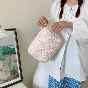 Gros plan sur la trousse de maquillage rose matelassée à motif floral avec fermeture