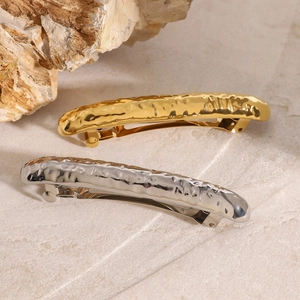 Detail of gold and silver spring hair clips featuring modern hammered lava texture